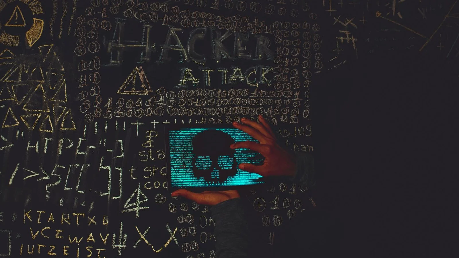 Cyberattaque malware - main tenant écran lumineux avec crâne et code hacker