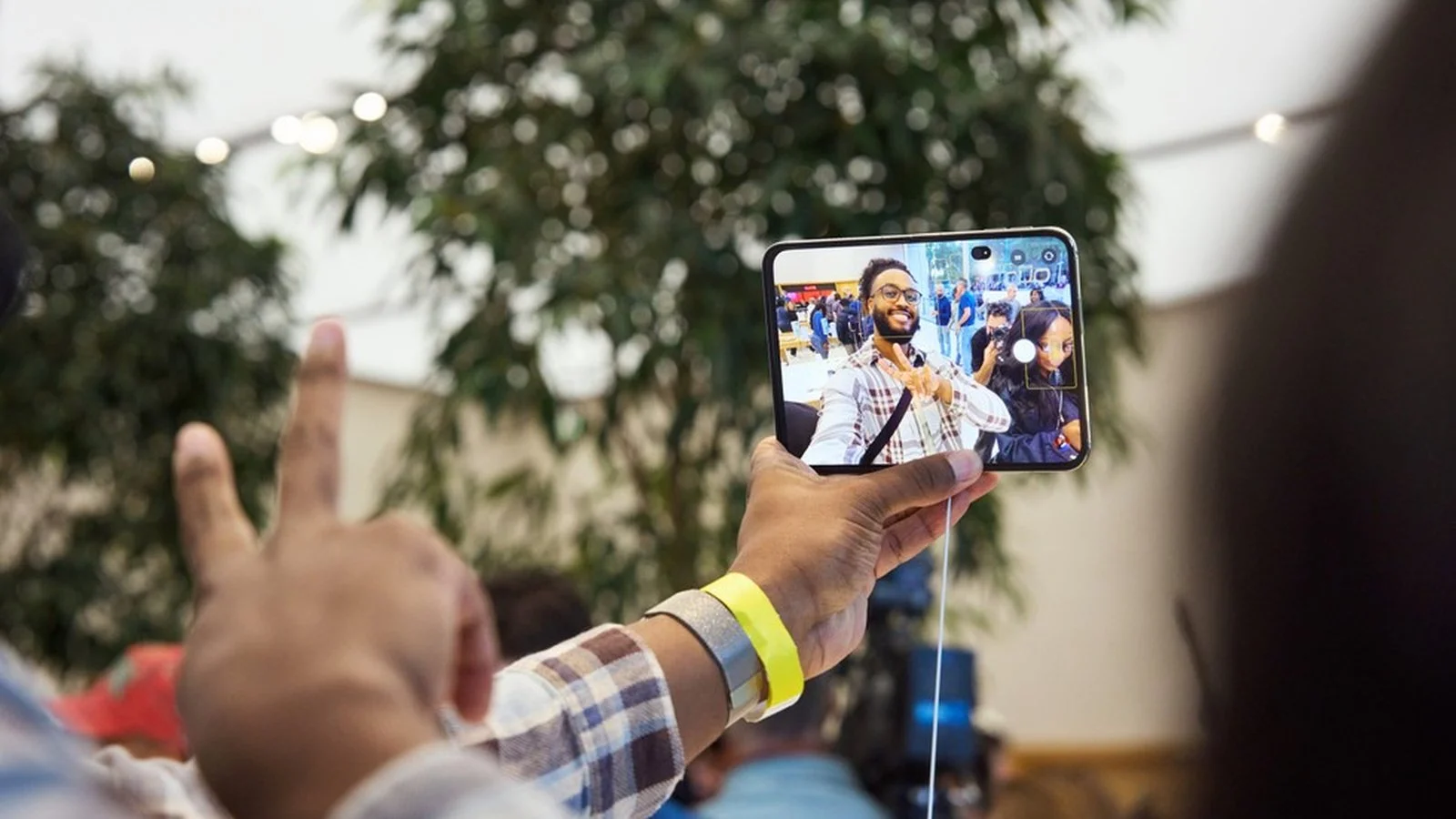 Smartphone pliable photographiant des clients, un iPhone Duo en démonstration dans un Apple Store