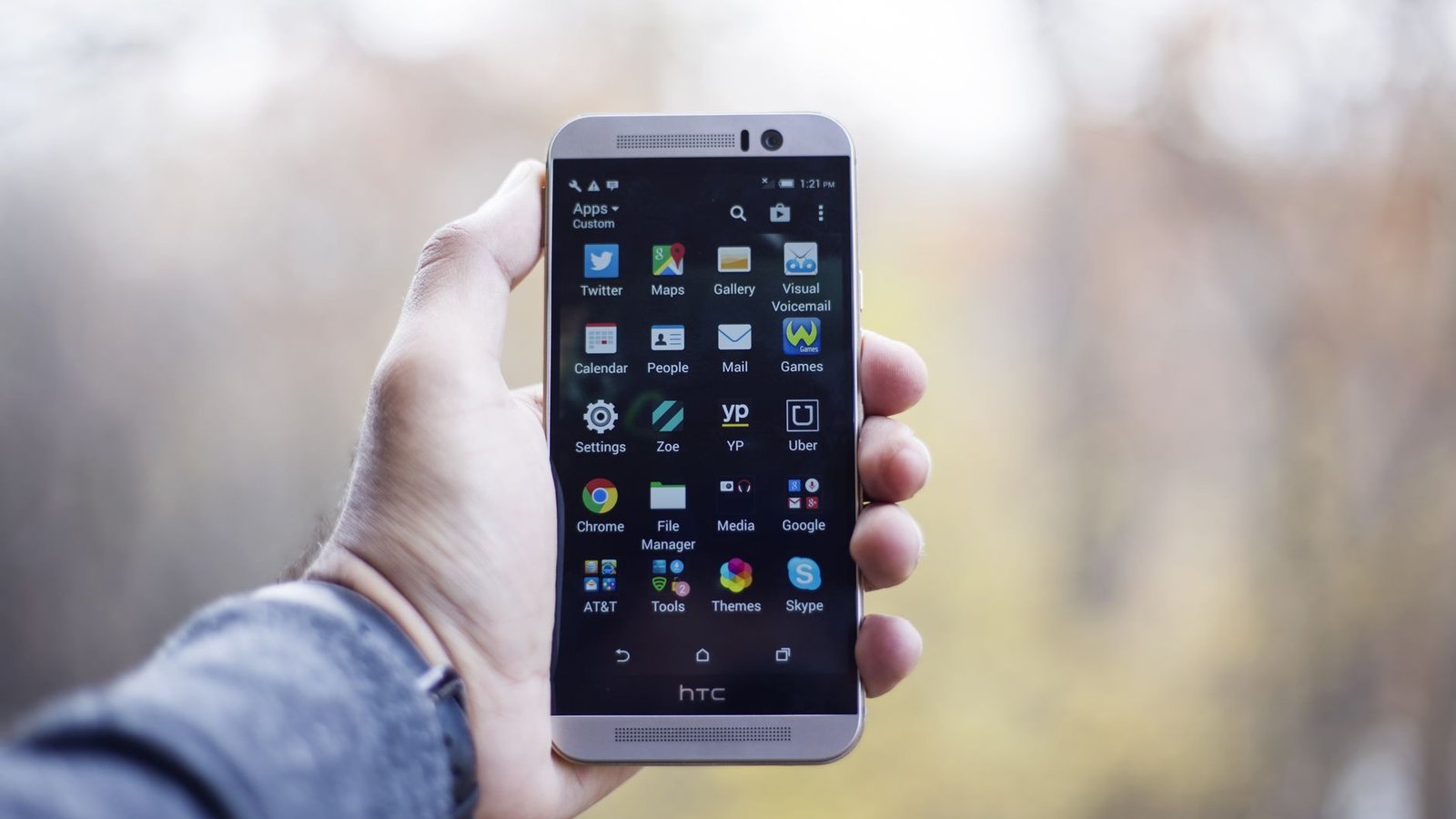 Smartphone HTC tenu en main avec écran d'accueil Android visible