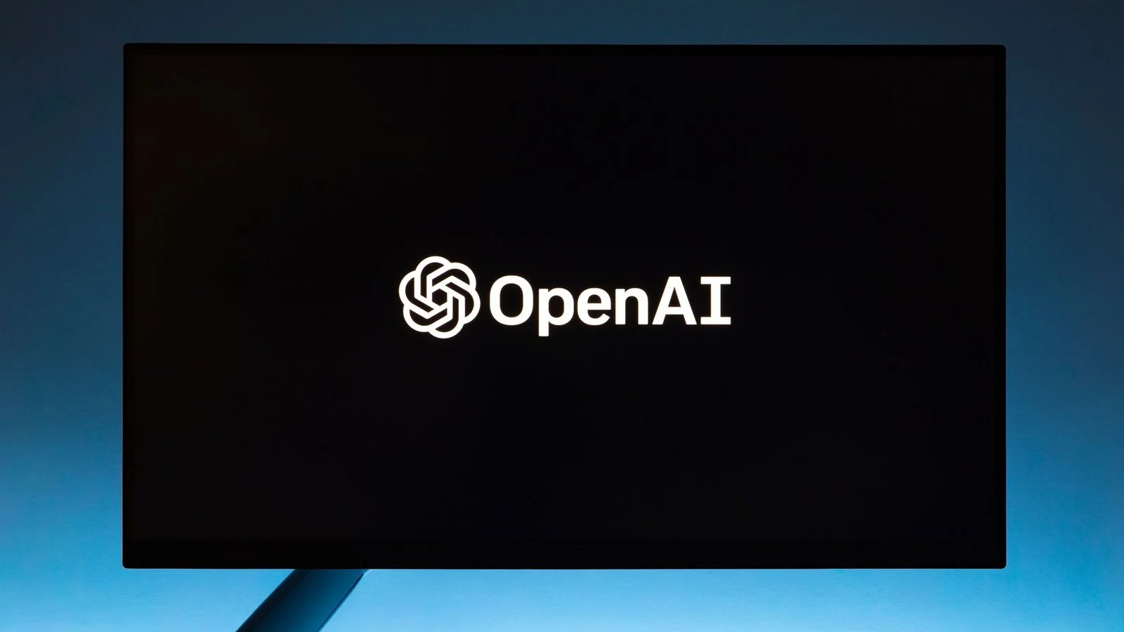 Logo OpenAI sur écran noir fond bleu