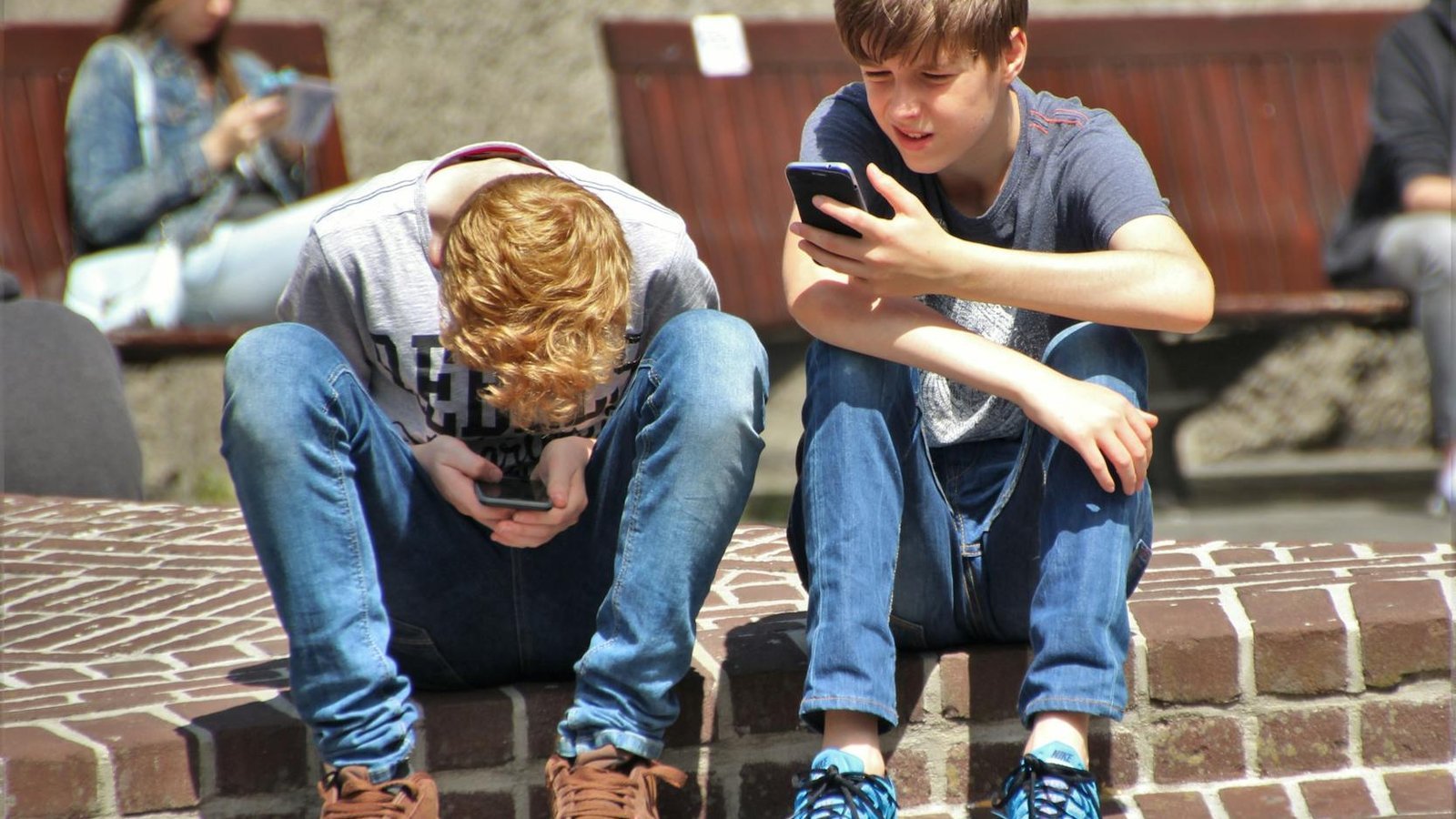Interdiction téléphone école — adolescents utilisant smartphones en plein air