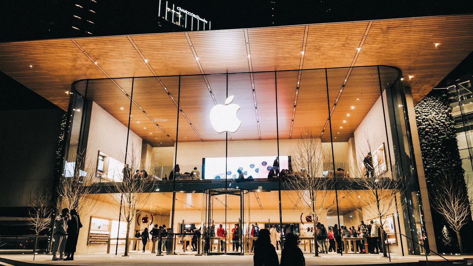 Apple Store façade en verre illuminée avec logo Apple la nuit