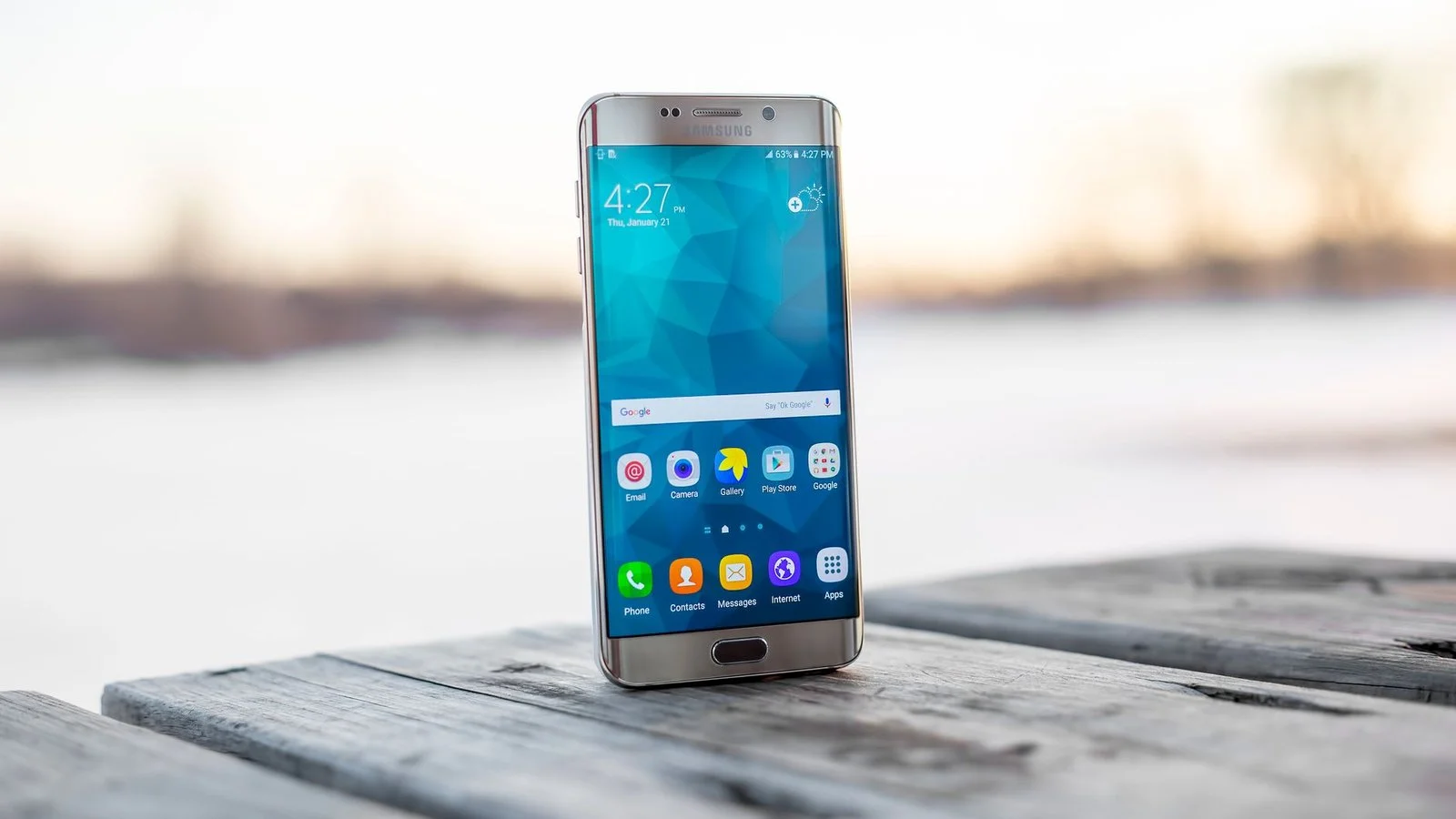 Samsung Galaxy smartphone avec écran allumé posé sur bois