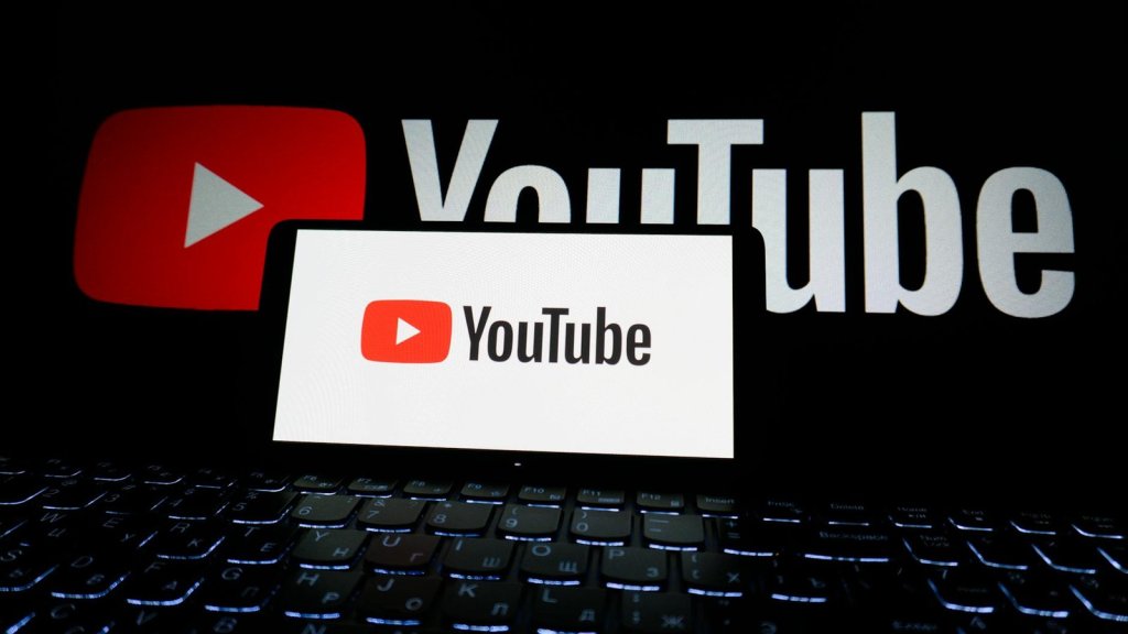 Close-up of YouTube logo displayed on a laptop screen in a dark environment.