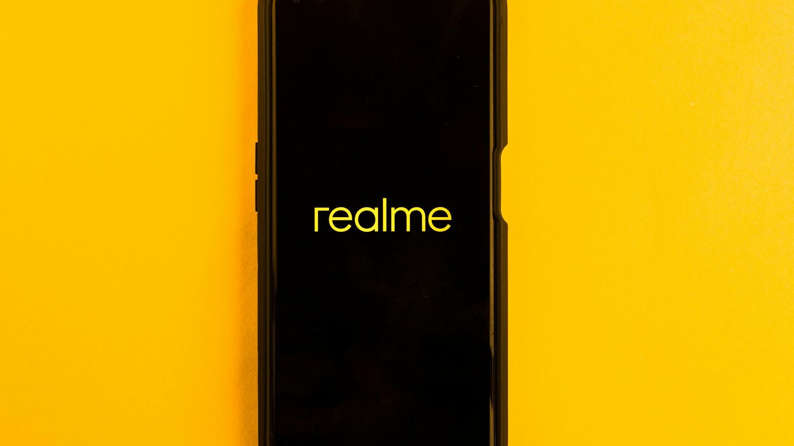 Realme smartphone displayed against a bright yellow backdrop, emphasizing modern technology.
