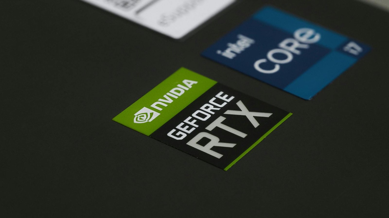Close-up of NVIDIA GeForce RTX and Intel Core i7 stickers on a laptop surface, showcasing modern technology.