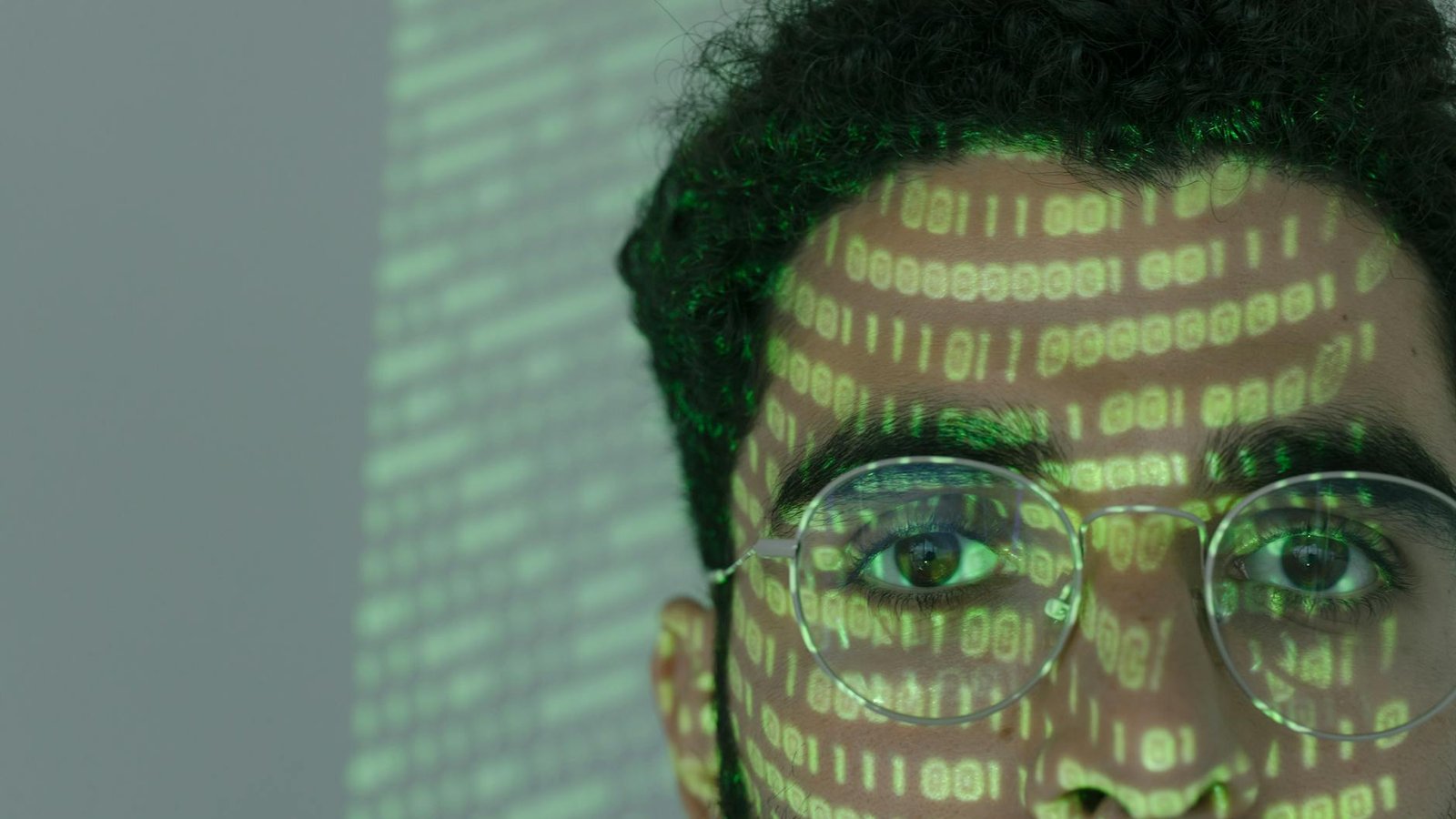Intelligence artificielle code binaire projeté sur visage homme lunettes