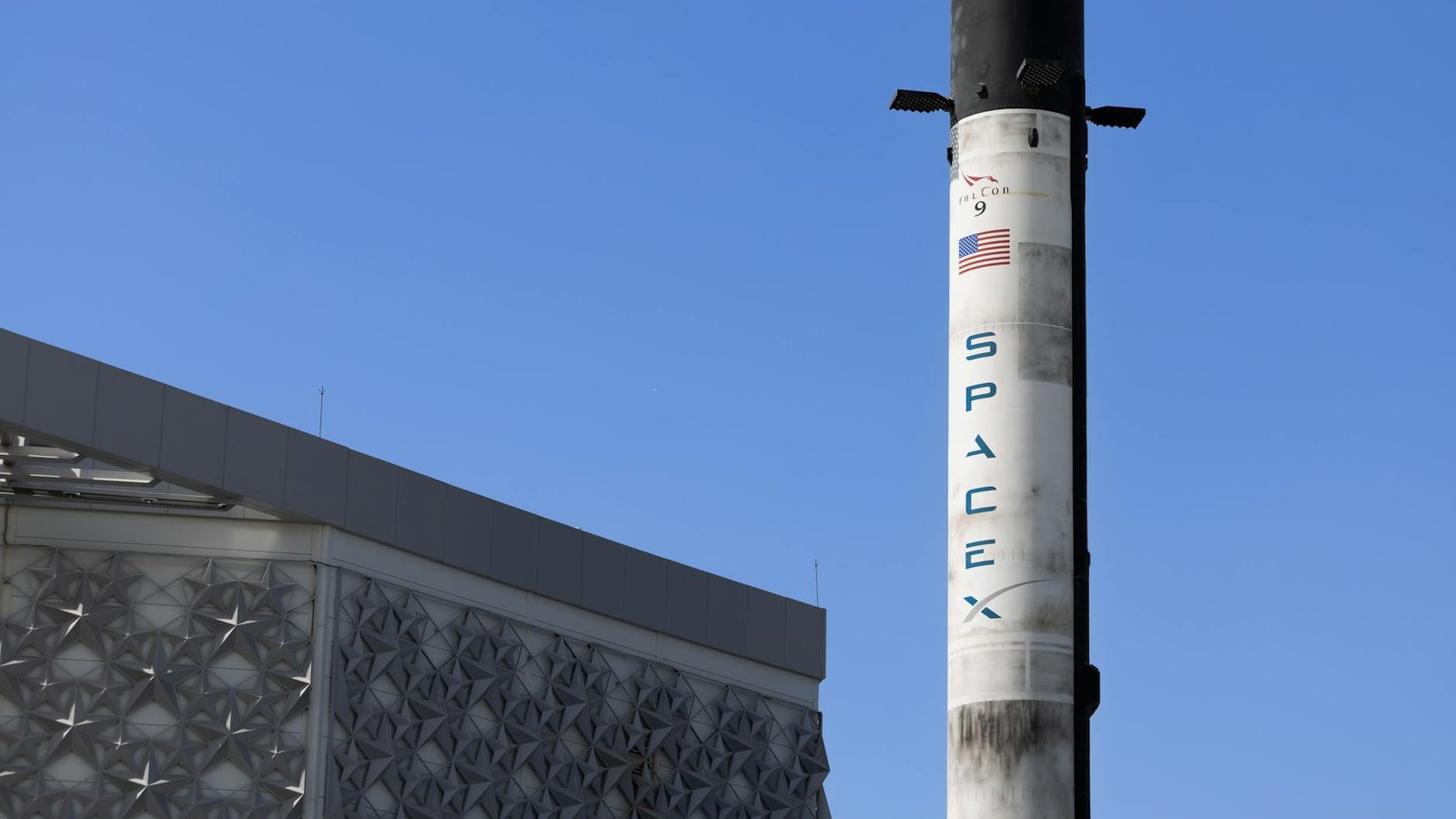 SpaceX booster Falcon 9 réutilisé avec logo bleu sur fond ciel bleu