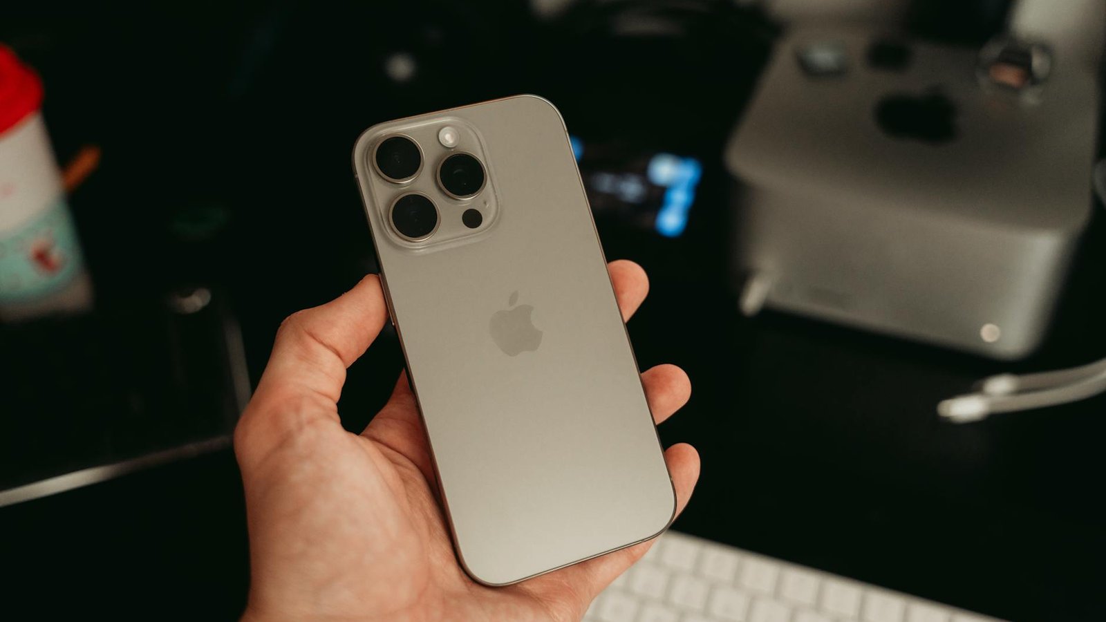 iPhone Pro titane puce A20 tenu en main bureau Apple
