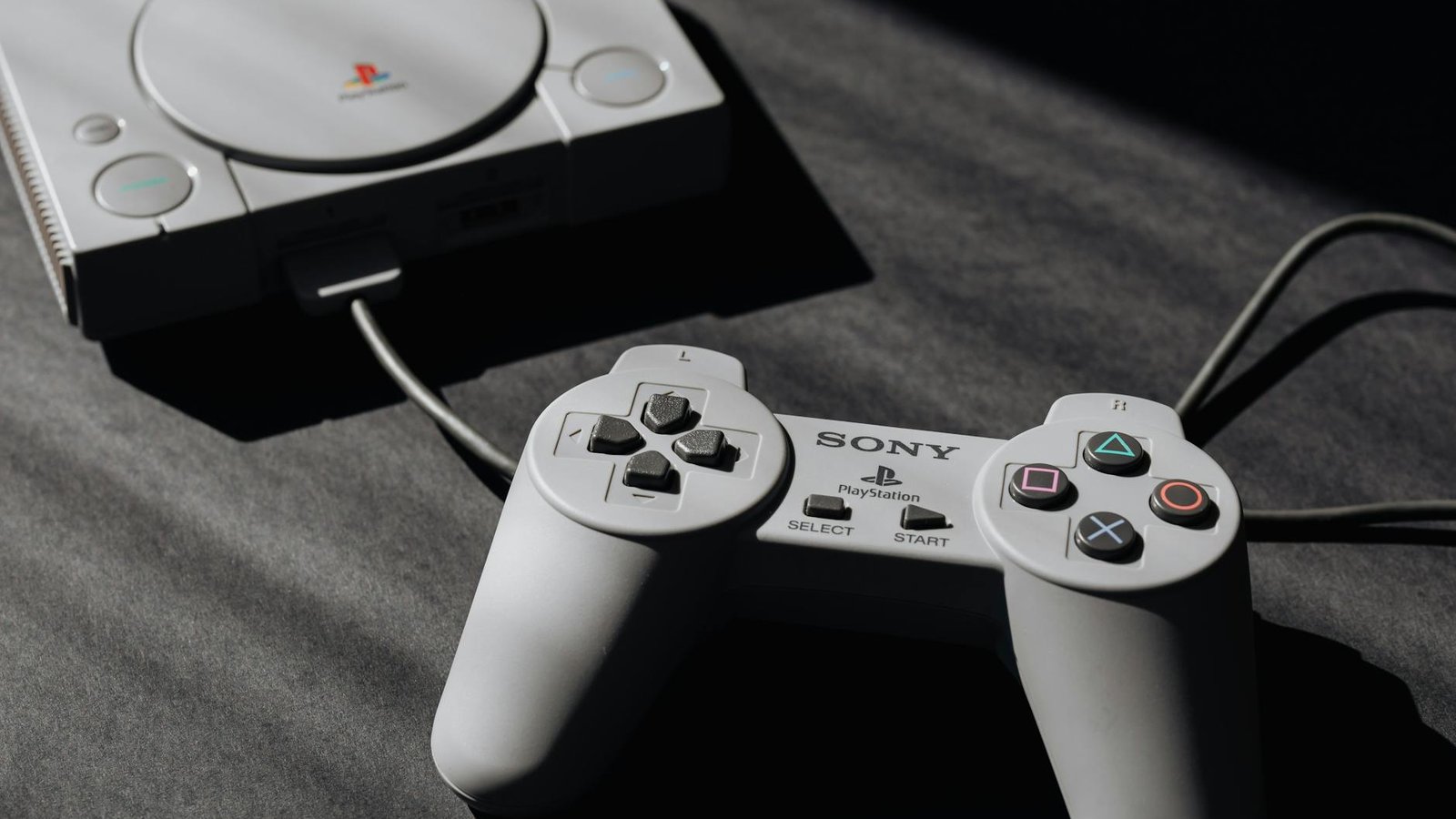 Console PlayStation Sony et manette filaire grise vintage