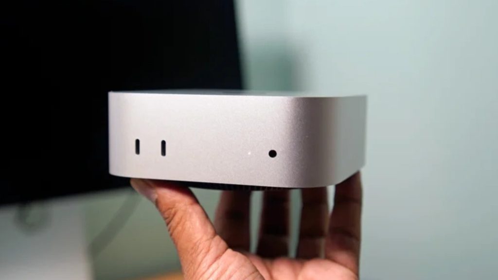 Mac mini Apple tenu en main, façade avant avec ports USB-C