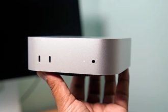 Mac mini Apple tenu en main, façade avant avec ports USB-C