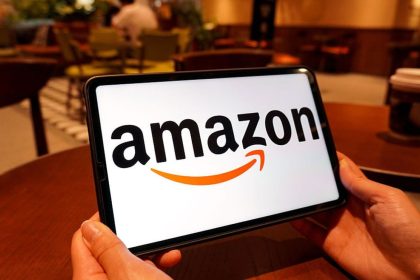 Logo Amazon sur smartphone tenu en mains dans un café